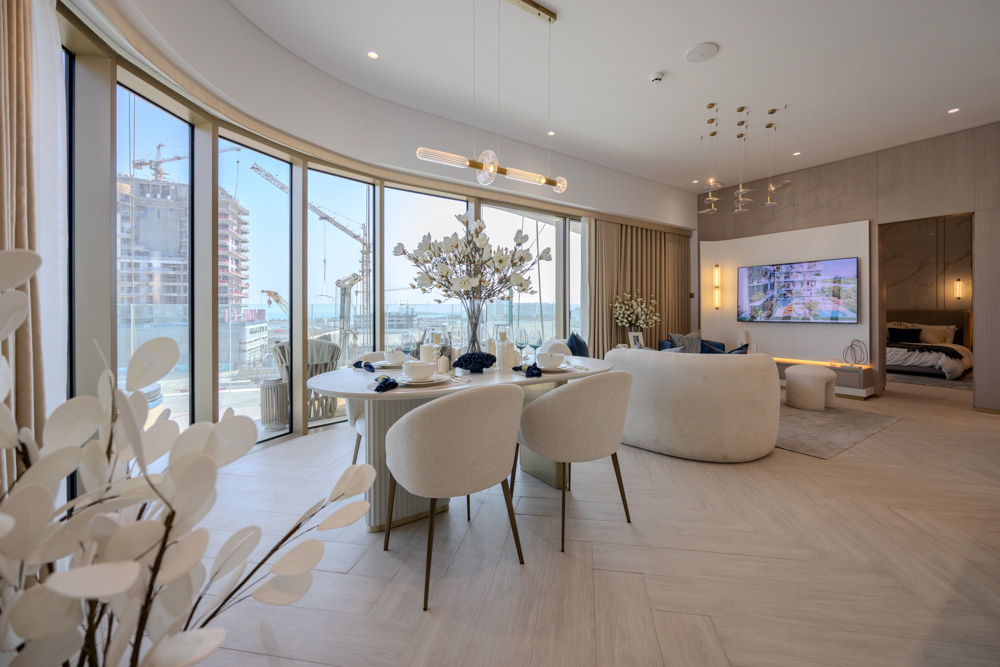 Beach Walk Residence A modern living space features a dining area, large windows, decorative plants, and a cozy bedroom nook.