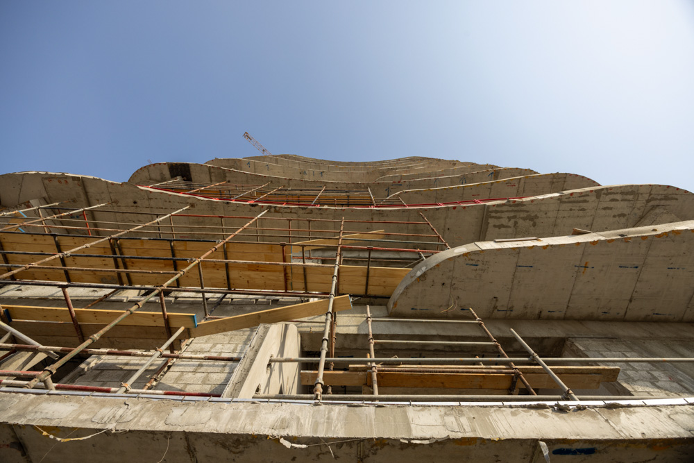 Beach Walk Iii By Imtiaz A construction site featuring scaffolding and a concrete building under development, viewed from below.