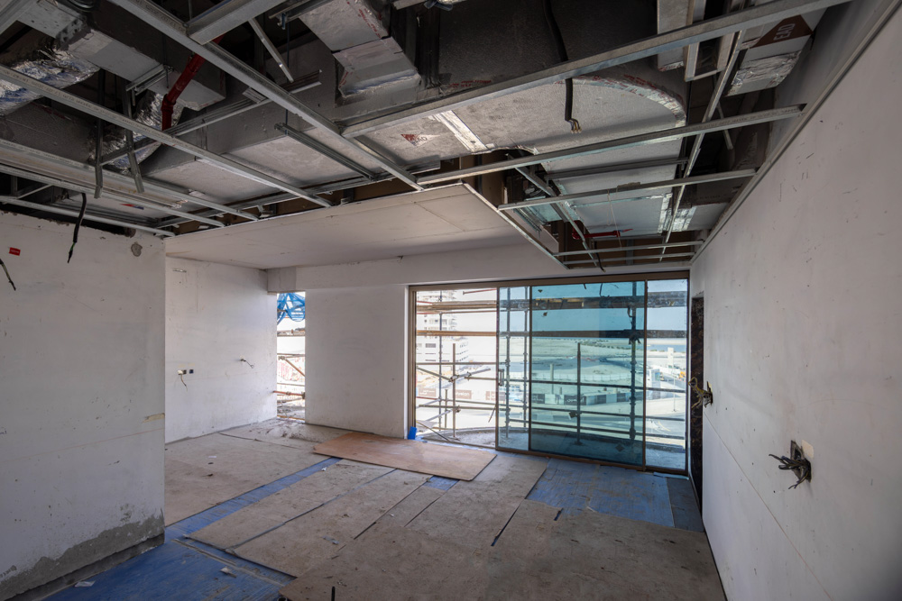Beach Walk Iii By Imtiaz An unfinished interior space with exposed ceilings, bare walls, and large windows under construction.