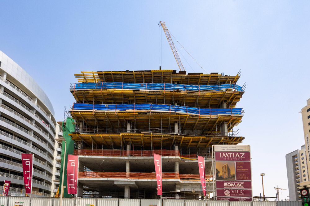Cove Edition I By Imtiaz 1 A construction site with a multi-story building under development, featuring scaffolding and construction signage.