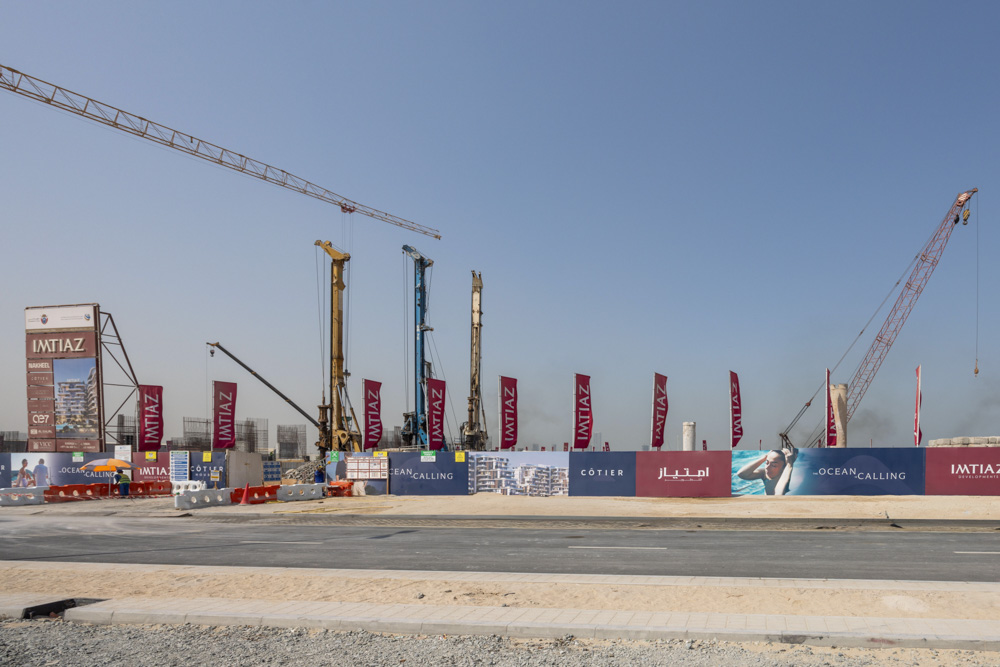 Cotier House 2 By Imtiaz A construction site featuring cranes, banners displaying "IMTIAZ," and a clear blue sky in the background.