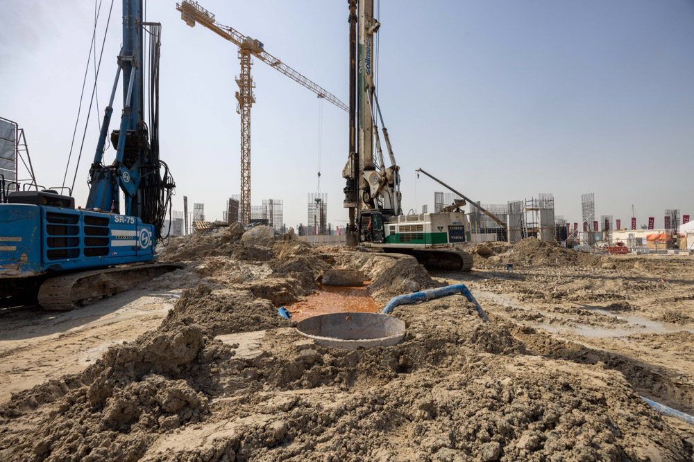 Cotier House 2 By Imtiaz Construction site with heavy machinery, cranes, and excavated earth under a clear sky.