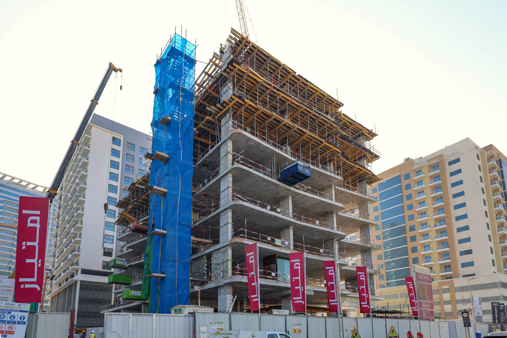 Cove Edition I By Imtiaz 1 A construction site showing a multi-story building under construction with cranes and safety barriers.