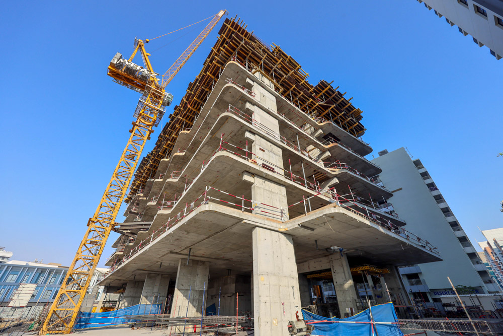 Cove Edition I By Imtiaz 1 A construction site featuring a partially built concrete structure and a yellow crane against a clear blue sky.
