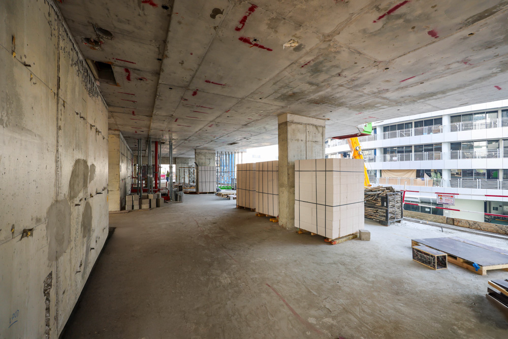 Cove Edition I By Imtiaz 1 An unfinished construction site featuring exposed concrete walls, stacks of building materials, and scaffolding.