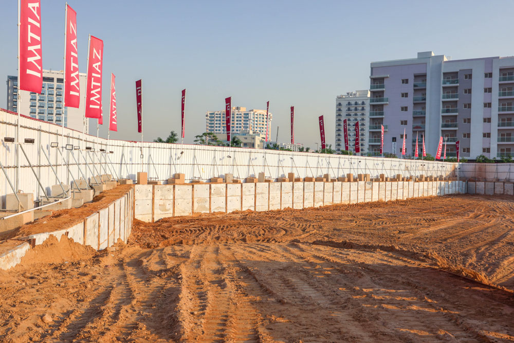 Cove Grand By Imtiaz Construction site featuring earth excavation, retaining walls, and branding banners against a clear sky.