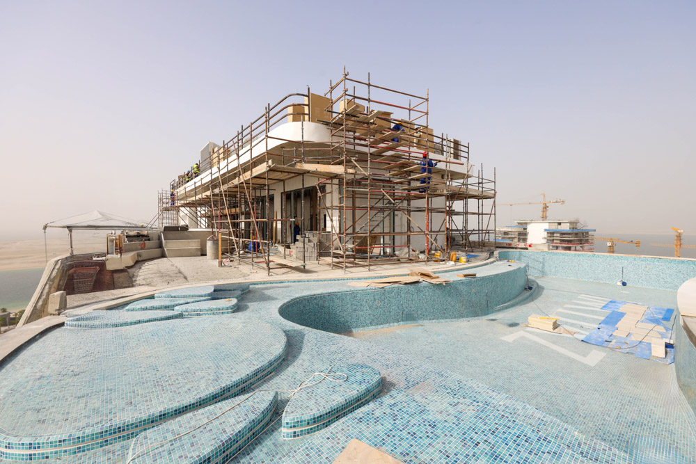Beach Walk Residence Construction site of a building with scaffolding and a partially finished pool, overlooking a distant landscape.