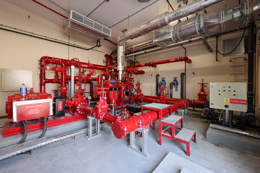 Beach Walk Residence A room filled with red piping and machinery, featuring valves, gauges, and a control panel.