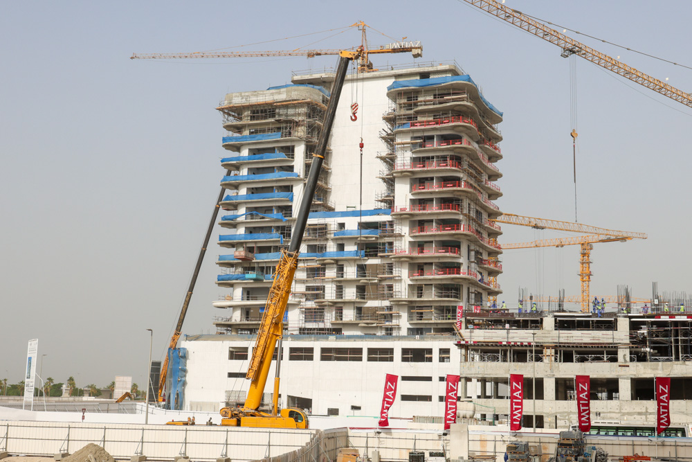 Beach Walk Iii By Imtiaz A construction site featuring a tall building with cranes, scaffolding, and construction workers in the background.