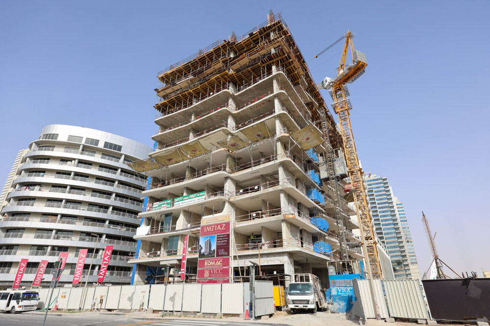 Cove Edition I By Imtiaz 1 A construction site featuring a partially built high-rise with a crane, surrounded by other buildings and signage.