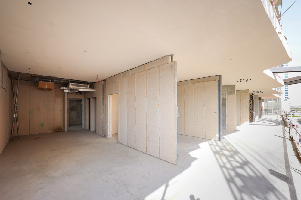 Cove Edition I By Imtiaz 1 An unfinished interior space with bare walls, exposed pipes, and doorways leading to different rooms.