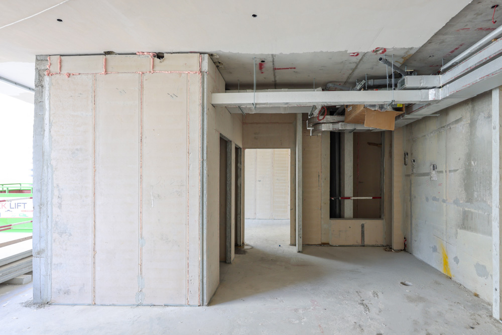 Cove Edition I By Imtiaz 1 An unfinished interior of a building under construction, featuring bare walls and exposed wiring.
