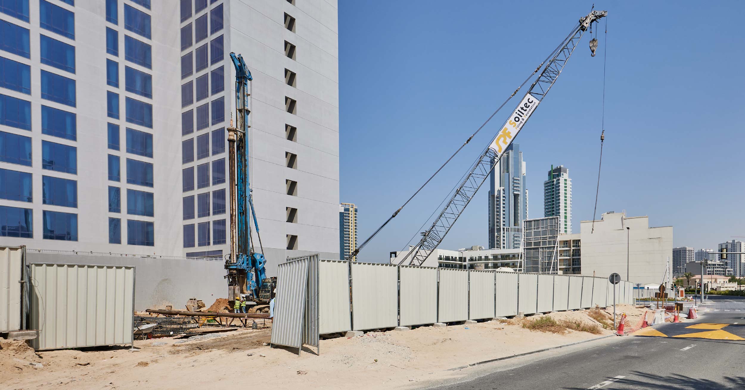 Pearl House By Imtiaz Construction site with cranes, a high-rise building, and fencing under a clear blue sky.