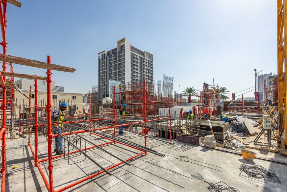 Pearl House By Imtiaz A busy construction site with workers in hard hats, scaffolding, and modern buildings in the background.