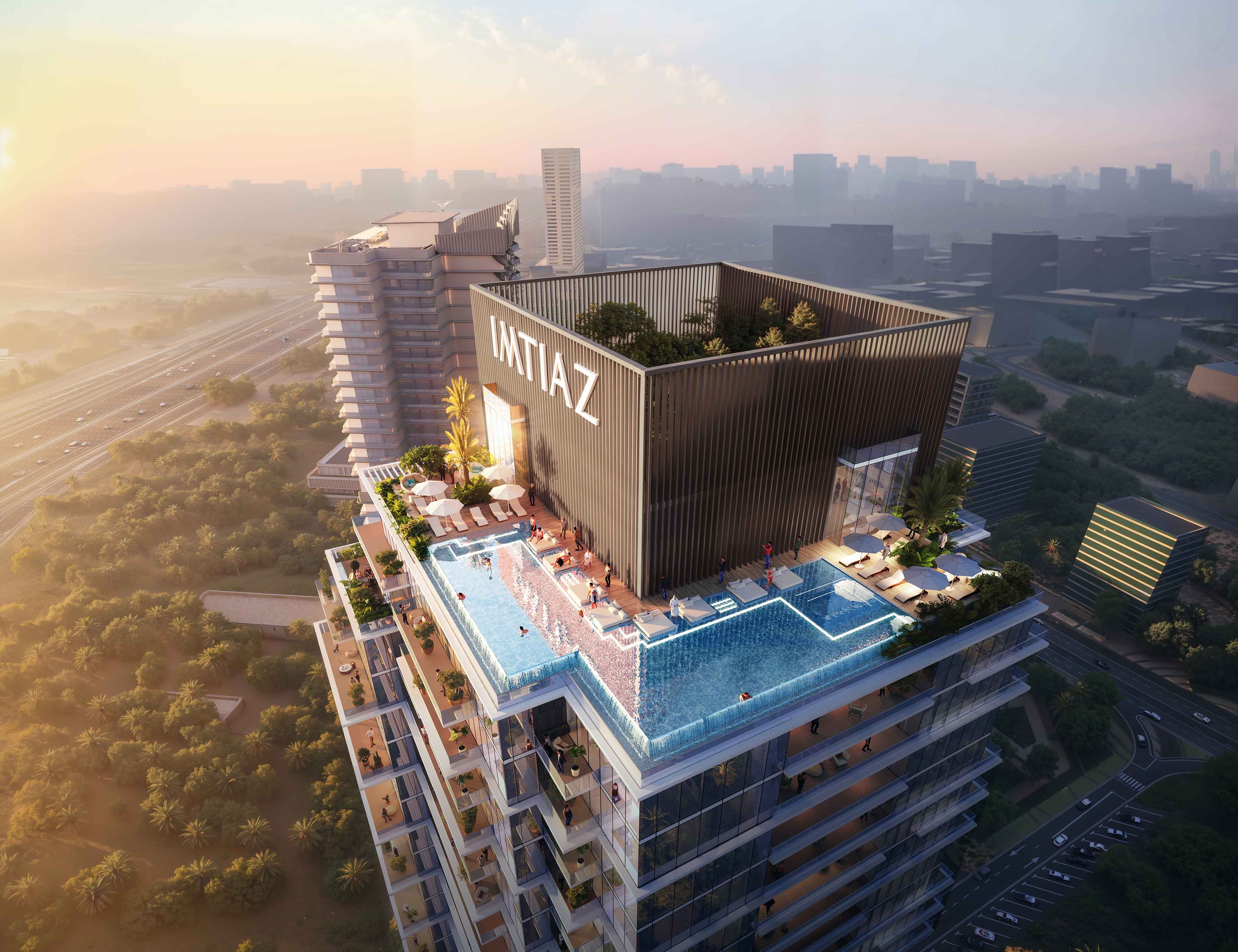 Cove Boulevard By Imtiaz A stunning rooftop pool at sunset atop a modern building, showcasing city views and lush greenery below.