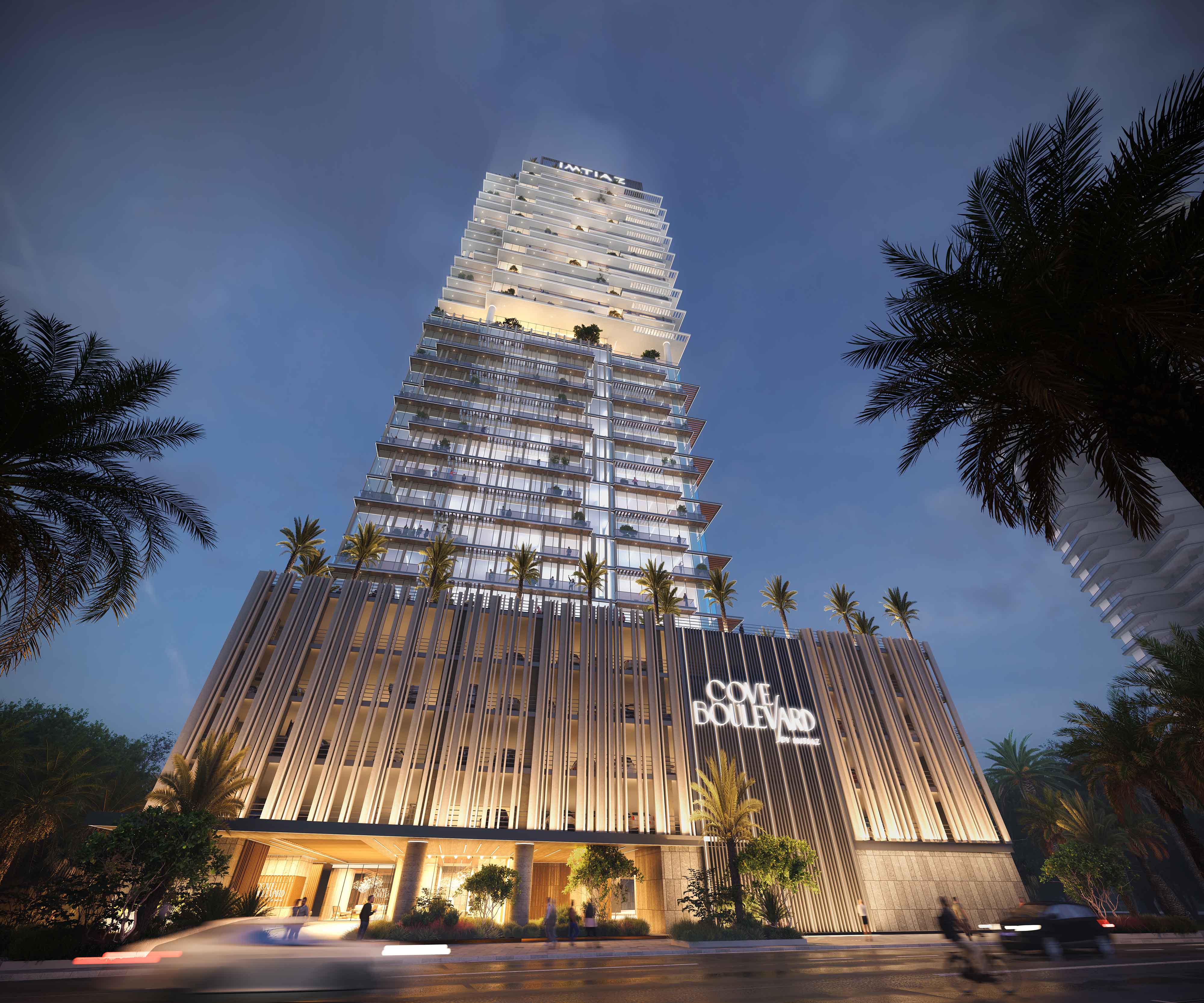 Cove Boulevard By Imtiaz A tall, modern building illuminated at night, featuring palm trees and a stylish entrance labeled "Cove Boulevard."
