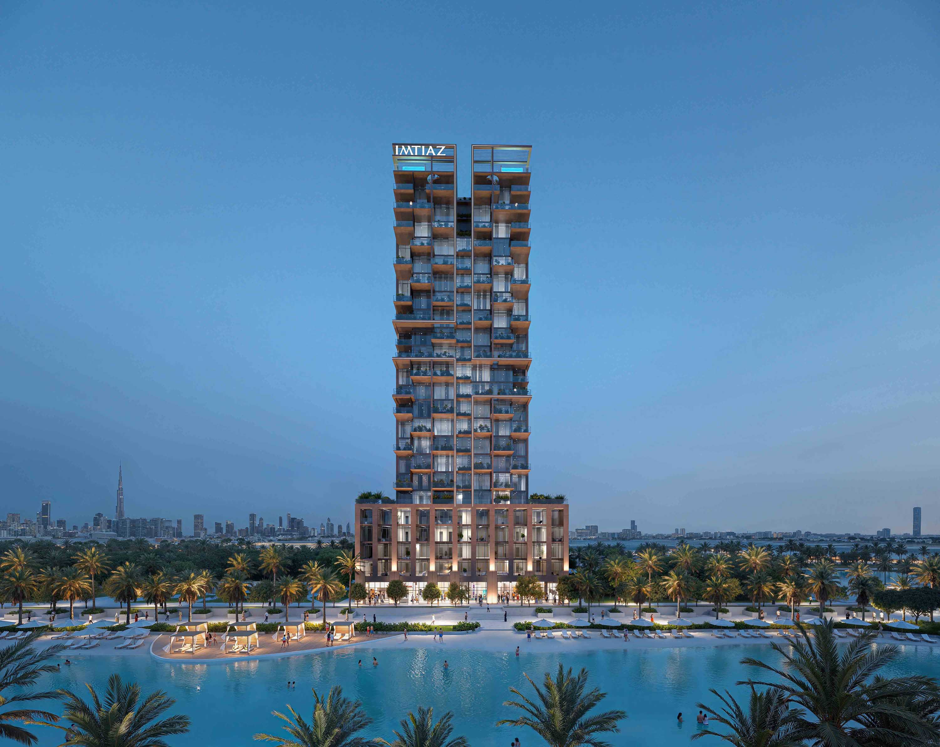 Wynwood Horizon By Imtiaz A modern high-rise building with balconies, surrounded by palm trees and a pool, against a city skyline at dusk.