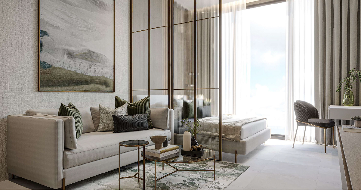 Westwood Grande By Imtiaz A modern living space featuring a light couch, decorative pillows, a glass coffee table, and a bed behind a partition.